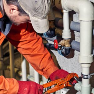 Plumber conducting preventive maintenance under a kitchen sink in a modern home.
