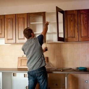 Man installing wooden cabinets.