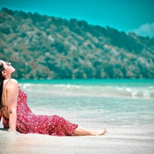 Solo traveler relaxing on a quiet sandy beach with clear blue water and sunny sky