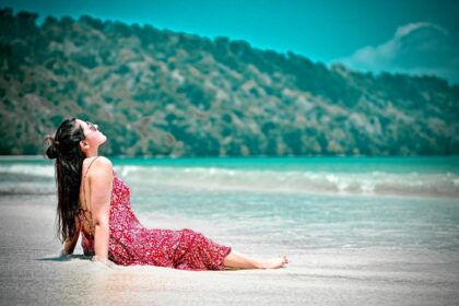 Solo traveler relaxing on a quiet sandy beach with clear blue water and sunny sky